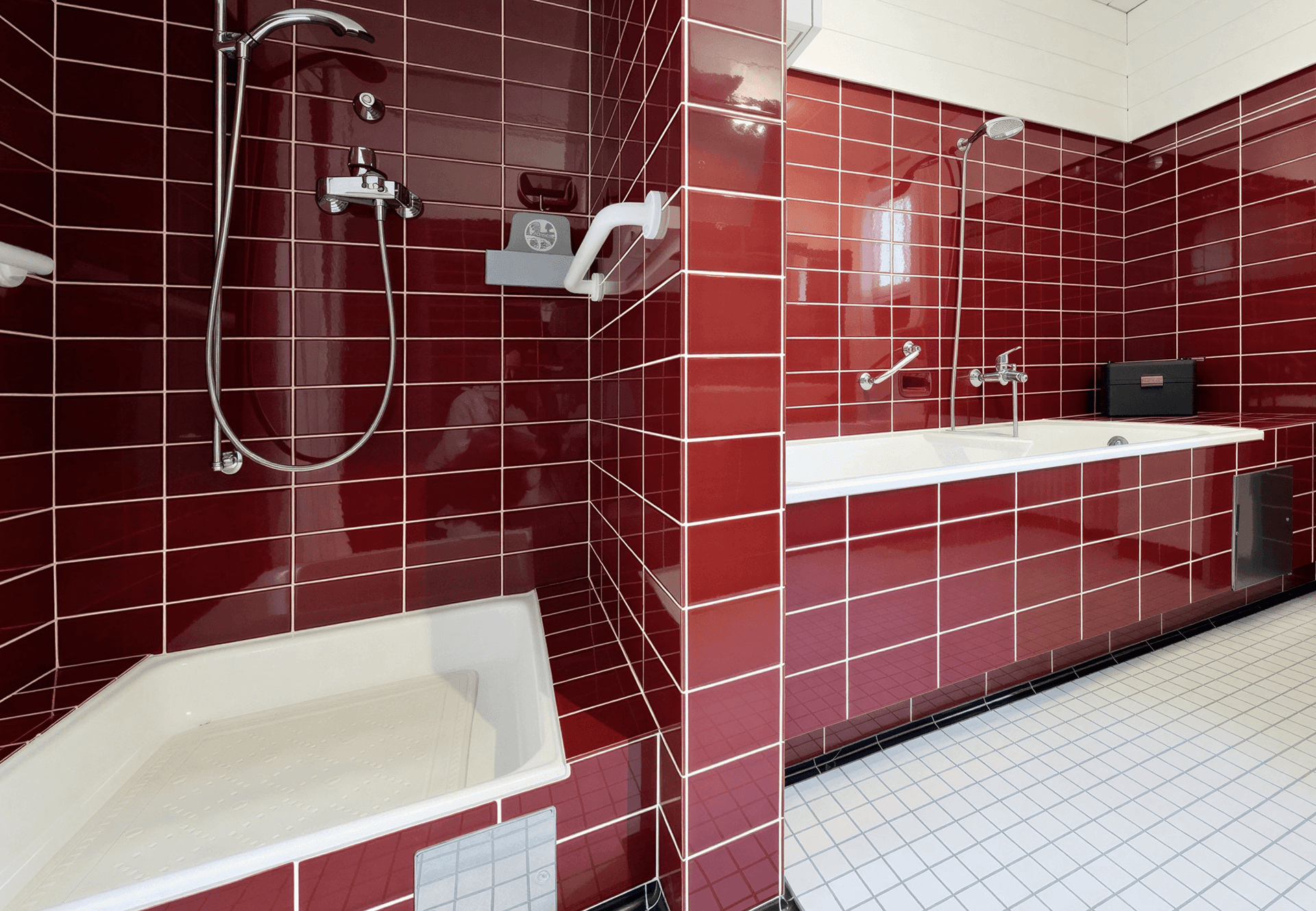 Dusch- und Badewannenbereich im Badezimmer mit auffälligen roten Wandfliesen und weißen Bodenfliesen.