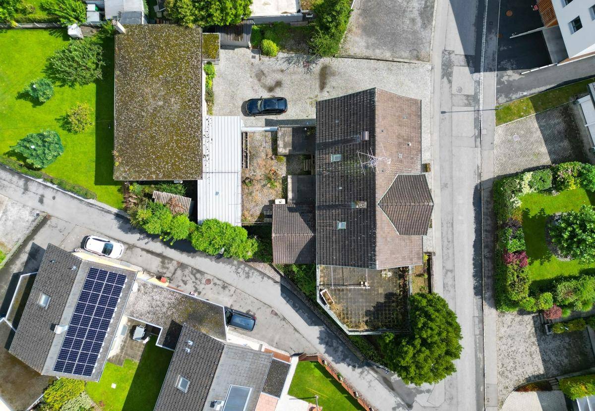Senkrechte Draufsicht auf das Grundstück mit Wohnhaus, Nebengebäuden und gepflasterten Flächen.