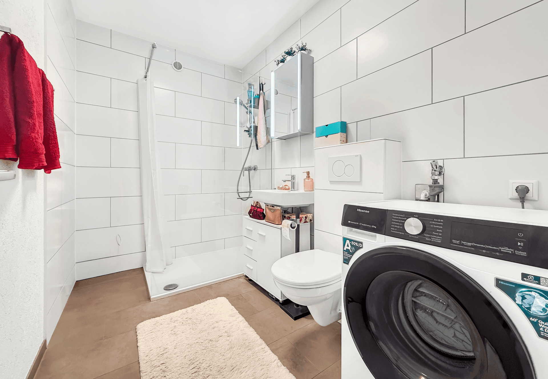 Modernes Badezimmer mit großer Dusche, Waschmaschine und weißen Fliesen.