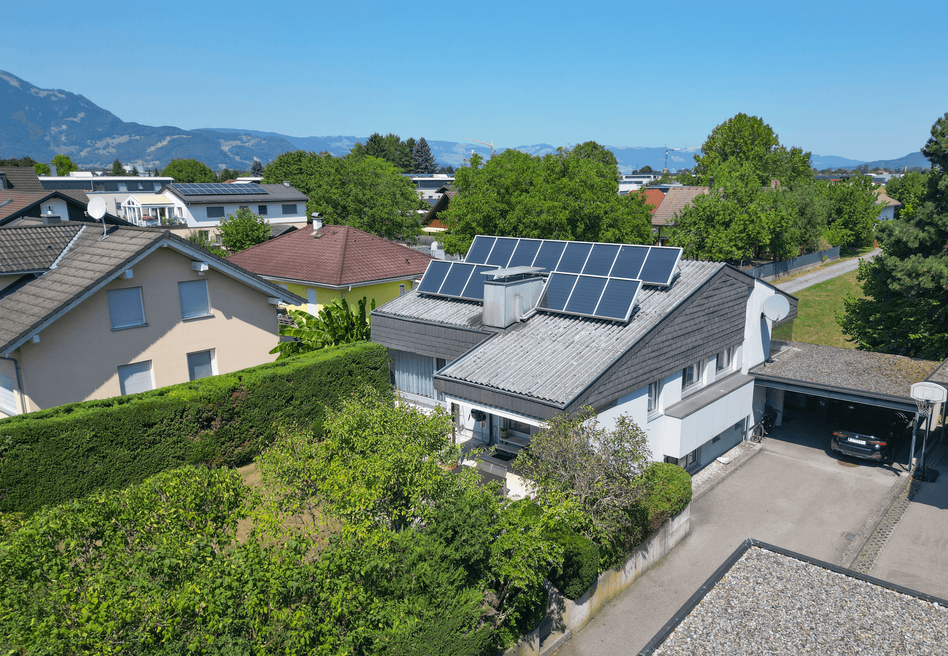 Luftaufnahme des Hauses mit Solaranlage, Carport und umliegender Wohngegend.