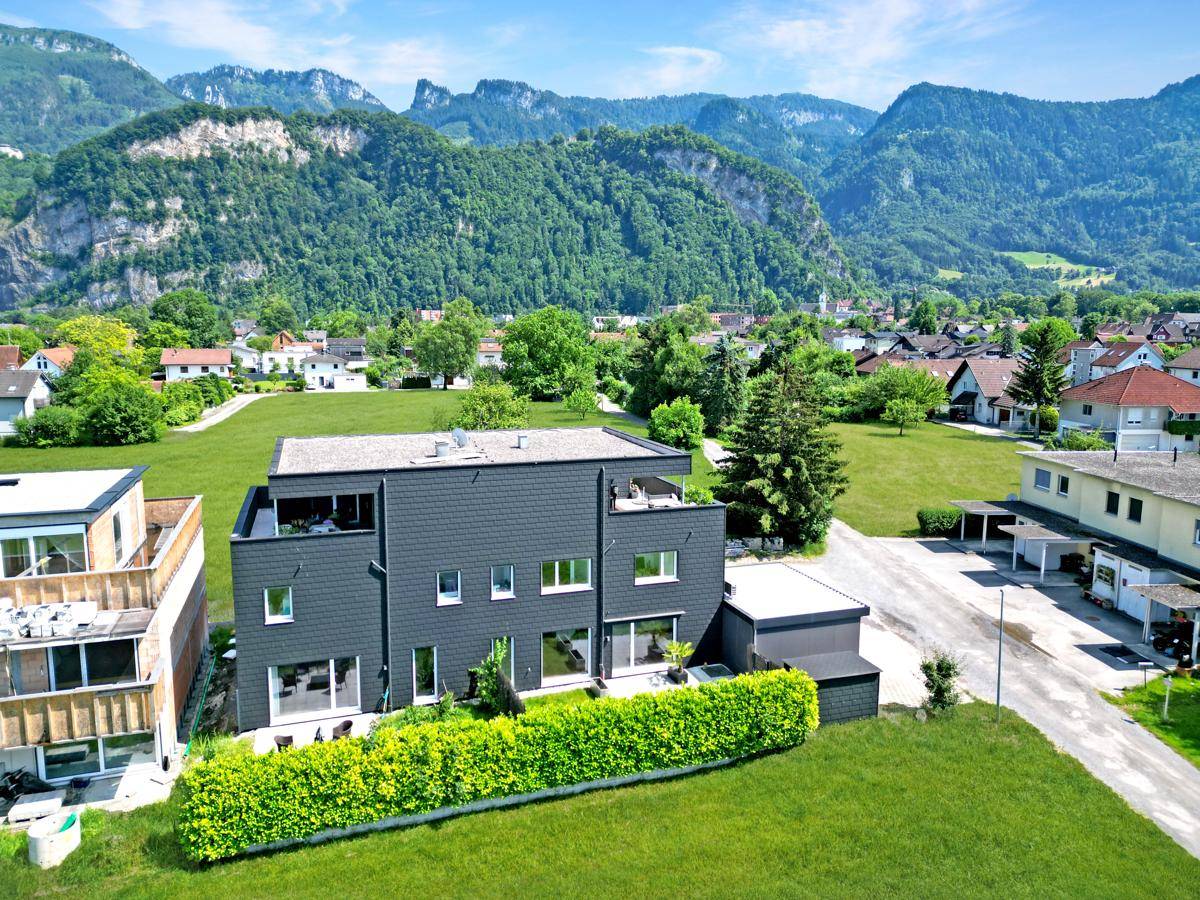 Luftaufnahme eines modernen Gebäudes in ländlicher Umgebung mit Bergen im Hintergrund.