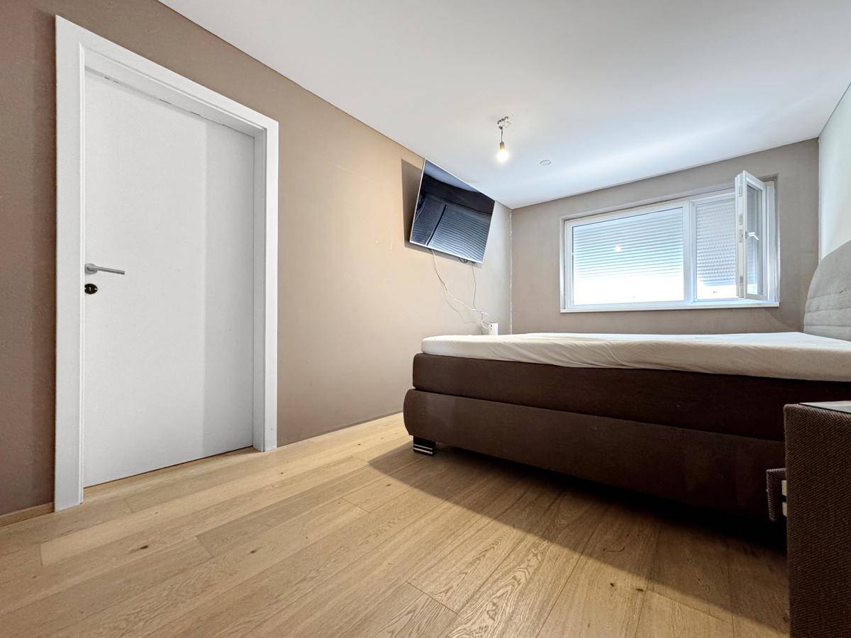 Schlafzimmer mit Holzboden, Doppelbett und einem Fenster für natürliches Licht.