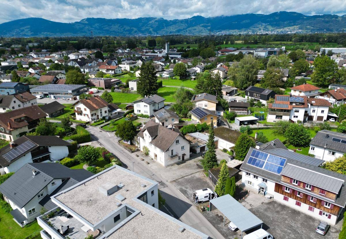 Panoramablick über die Wohnsiedlung mit vielen Dächern und grünen Gärten unter bewölktem Himmel.