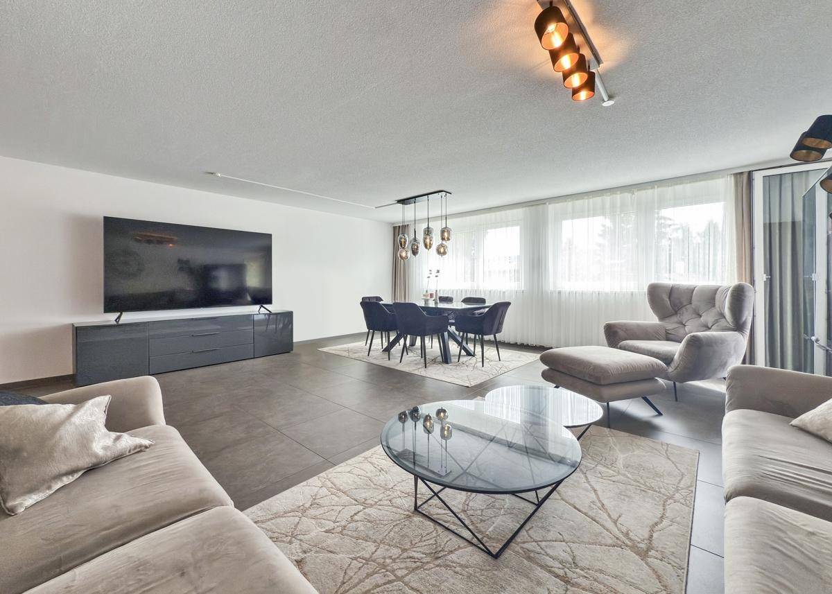 Heller Wohn-Essbereich mit großem Fernseher, Esstisch und bequemen Sofas.