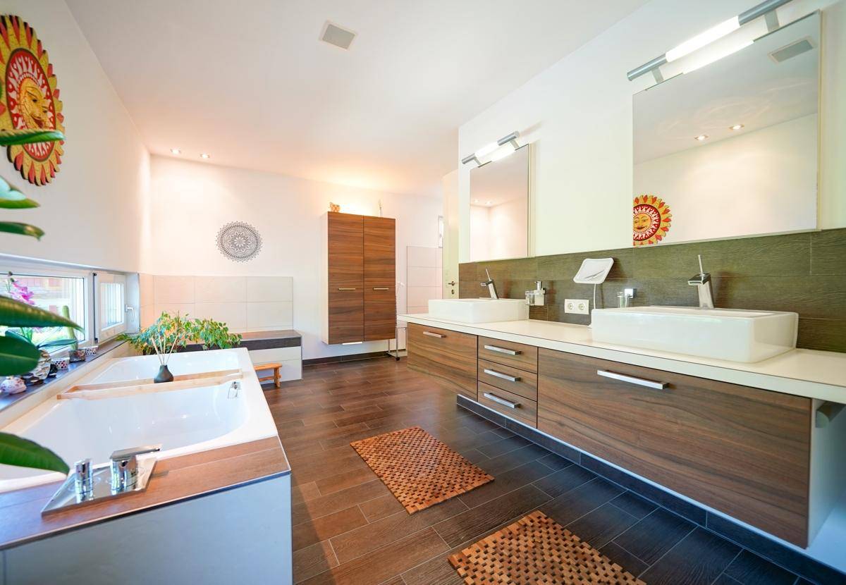 Großes Badezimmer mit Doppelwaschbecken, Badewanne und Holzmöbeln.
