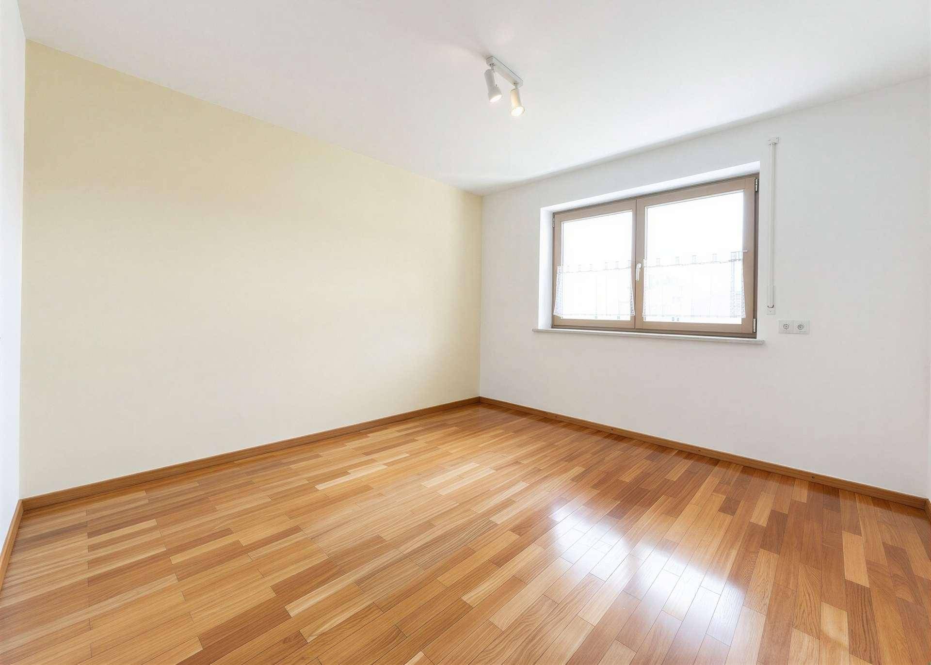 Leeres Schlafzimmer mit Holzboden und hellem Fenster, bereit zur individuellen Gestaltung.