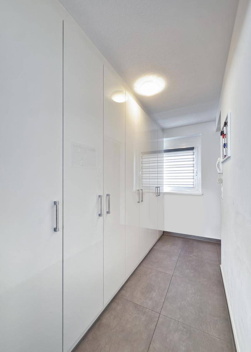 Heller Flur mit Einbauschränken und Fenster, bietet viel Stauraum.