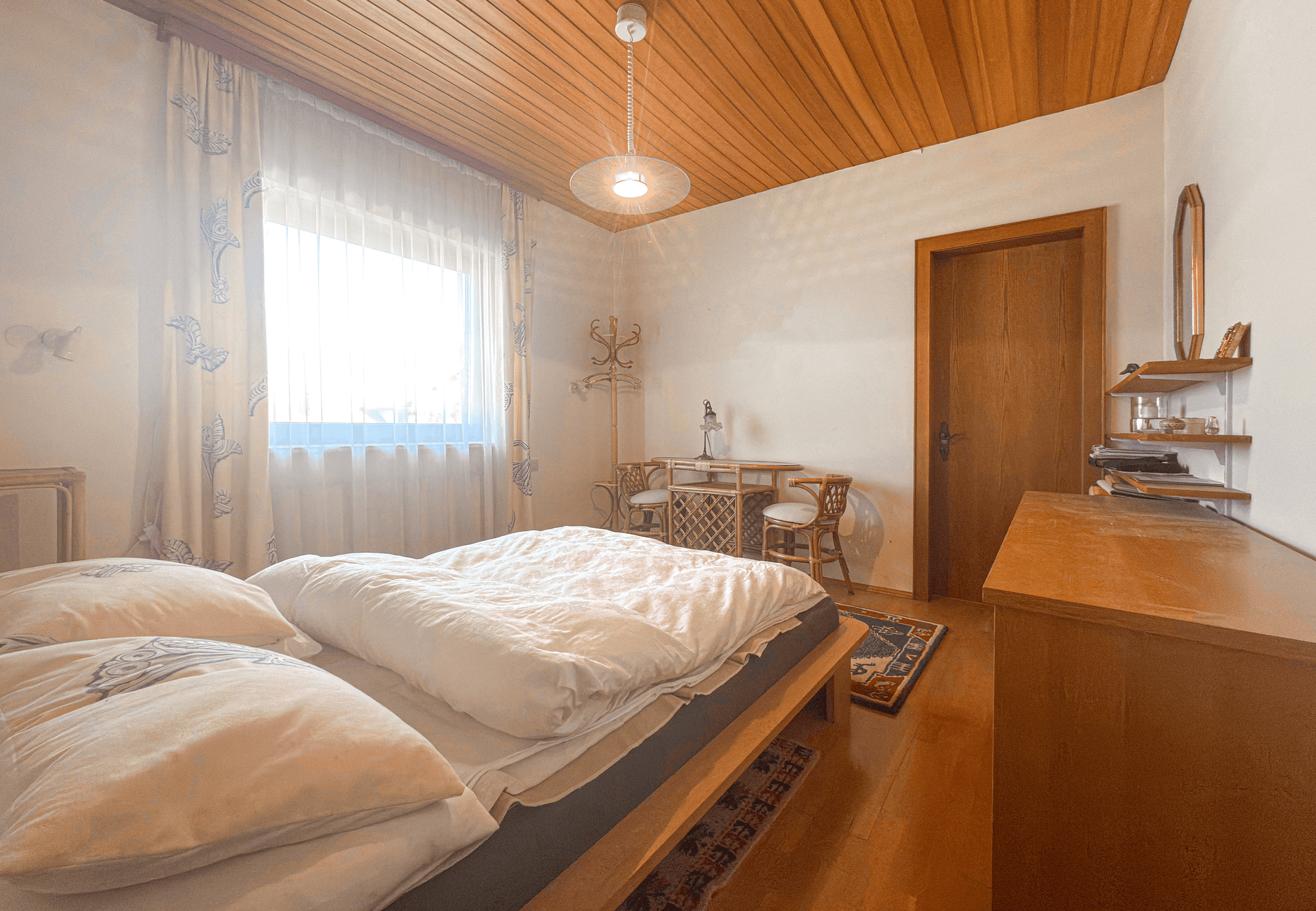 Gemütliches Schlafzimmer mit Holzdecke, Holzboden und Fenster für viel Tageslicht.