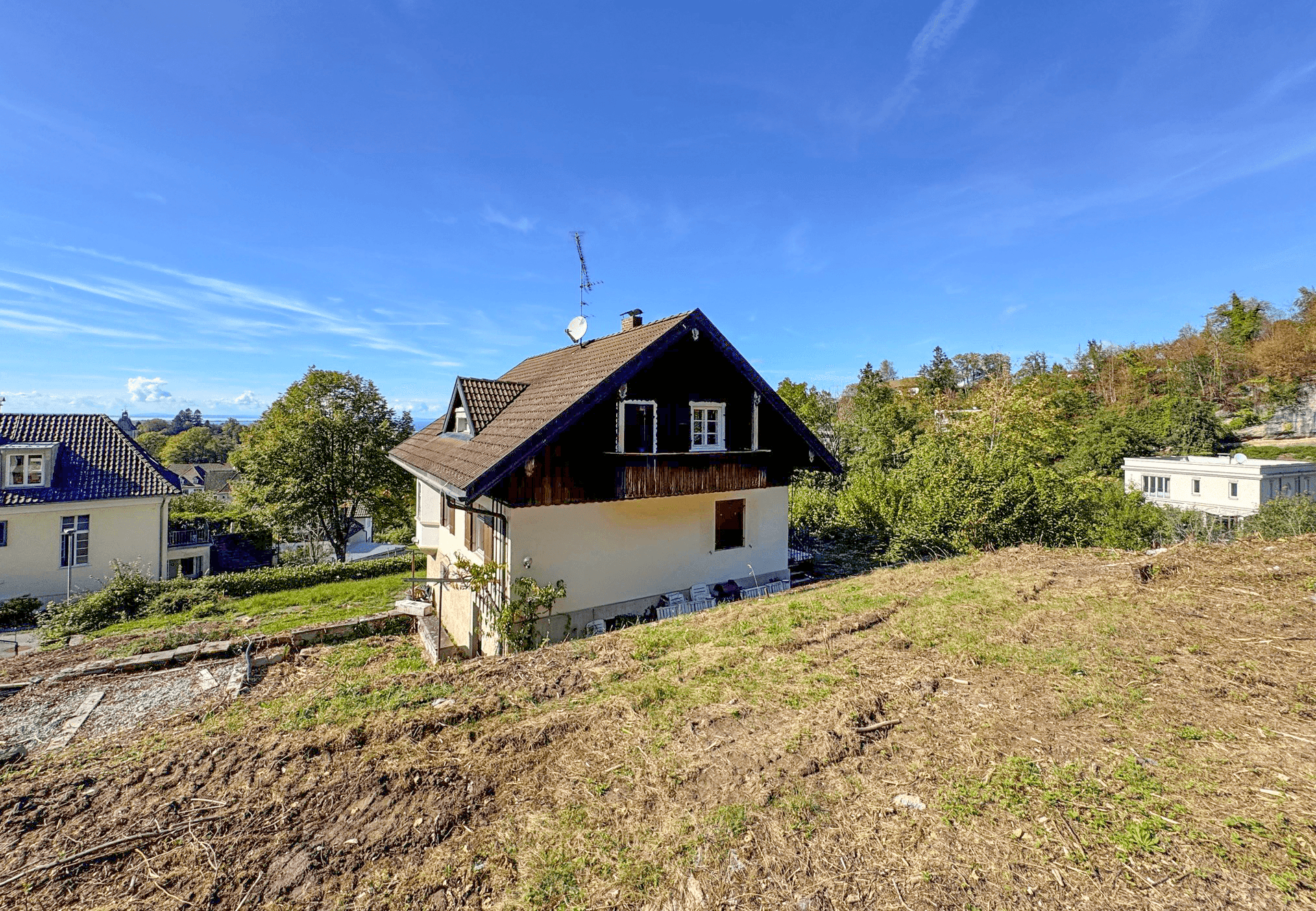Rückansicht des Hauses auf einem Hanggrundstück mit Blick auf die umliegende Natur und den Wald.