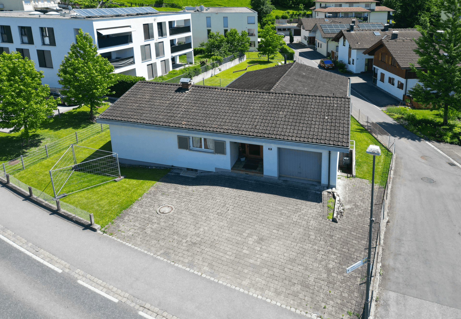 Luftaufnahme der Vorderseite des Hauses mit gepflasterter Einfahrt und integrierter Garage.