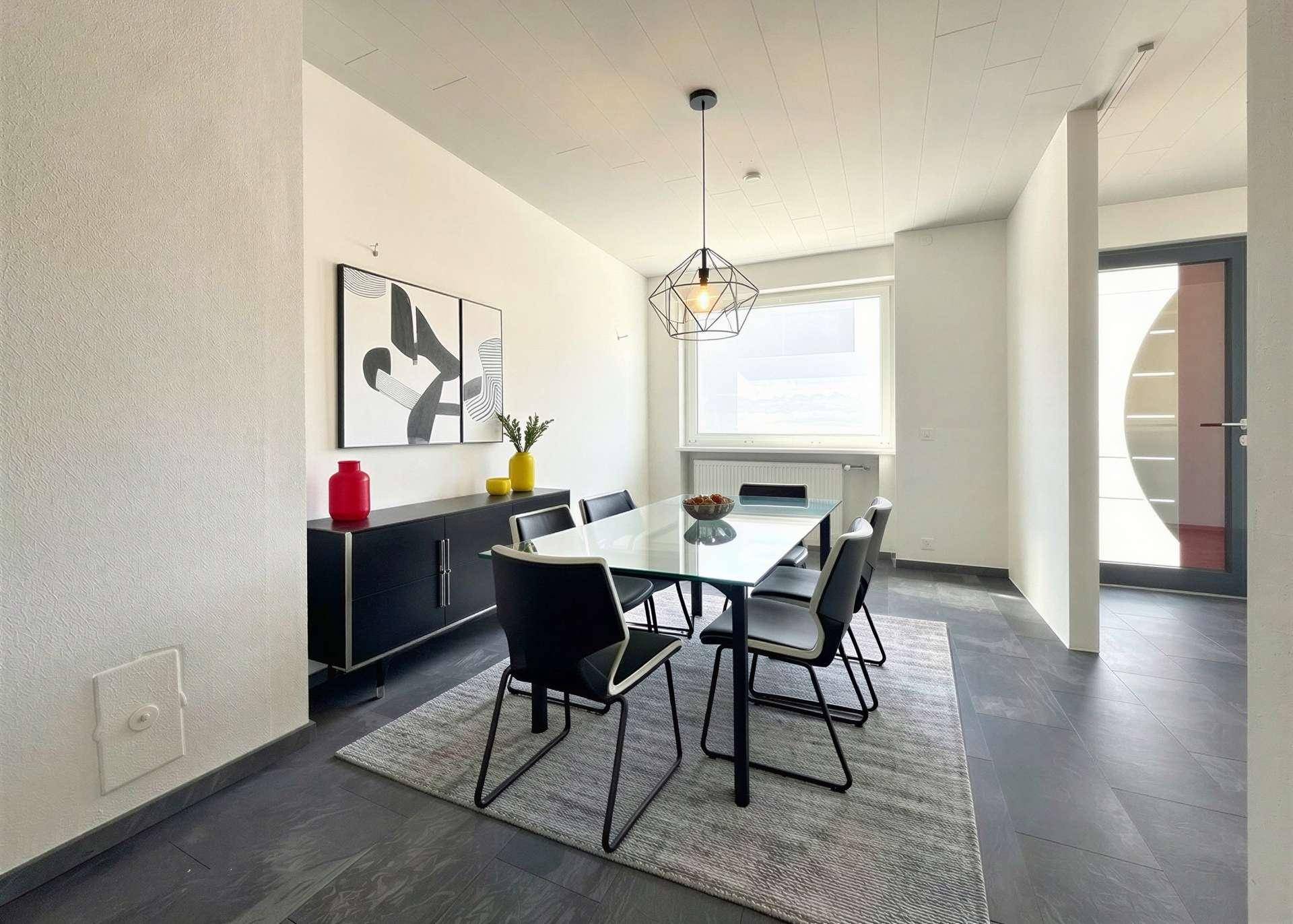 Eleganter Essbereich mit Glastisch, schwarzen Stühlen und modernem Sideboard.