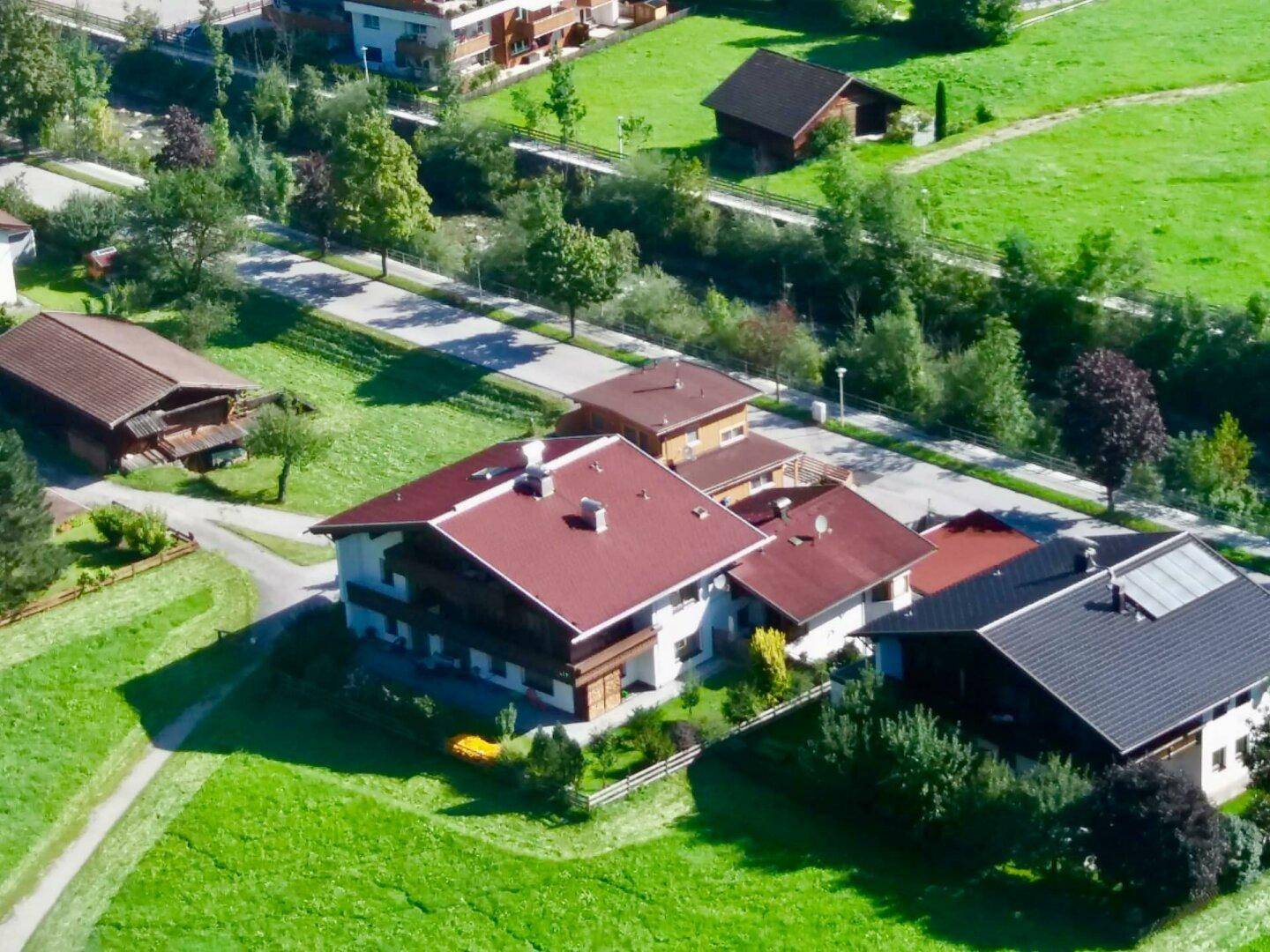 Luftaufnahme einer Wohnsiedlung mit Häusern, grünen Wiesen und einem Fluss in der Ferne.