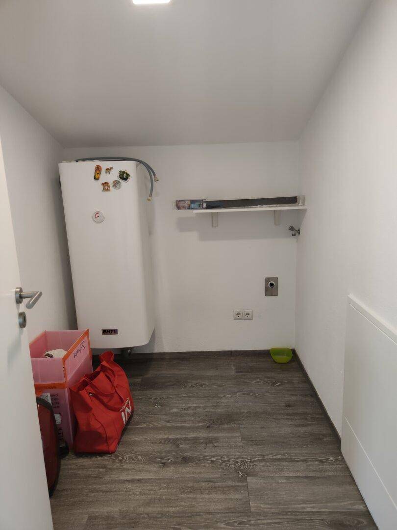 Praktischer Hauswirtschaftsraum mit Warmwasserbereiter und einfacher Ablagefläche.