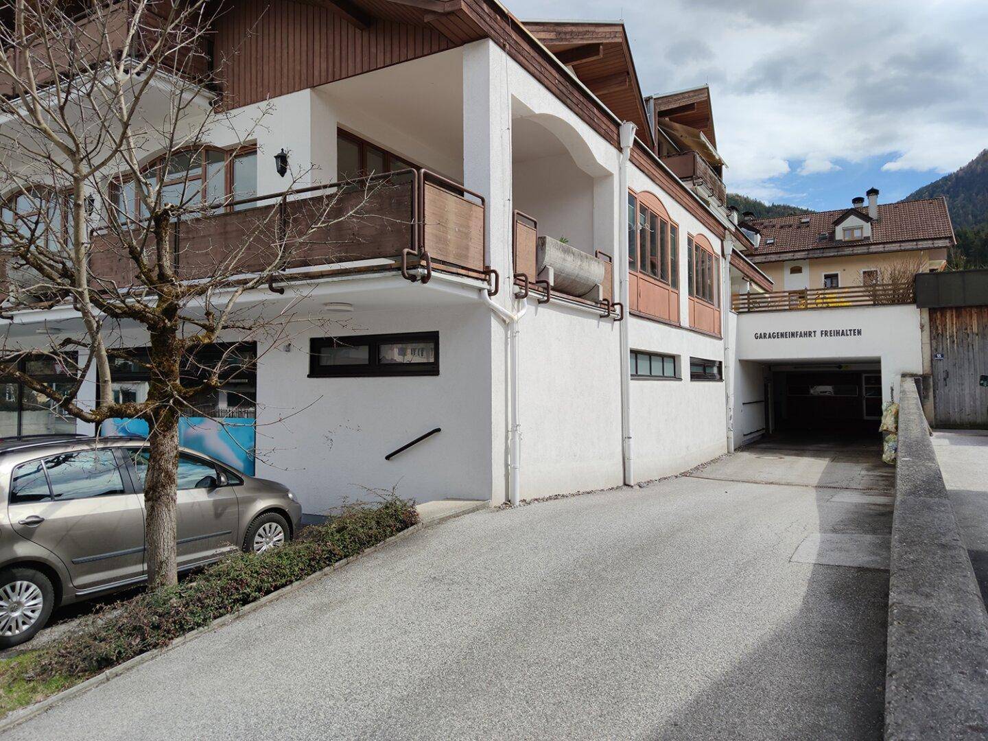 Seitenansicht des Gebäudes mit einer Einfahrt, die zu einer Tiefgarage führt.