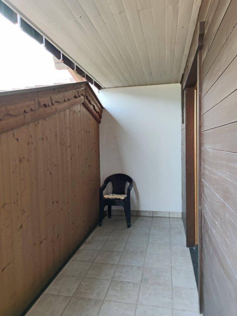Überdachter Balkon mit Fliesenboden und Holzverkleidung, ideal für entspannte Stunden im Freien.