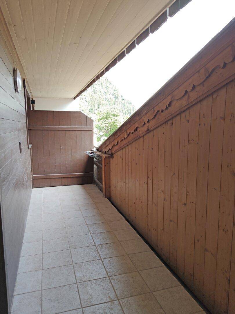 Langer, überdachter Balkon mit Holzverkleidung und Blick auf die umliegende Natur.
