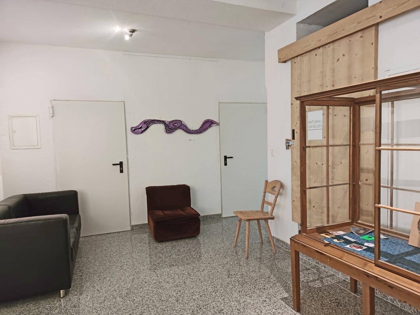 Empfangsbereich mit Sitzgelegenheiten, Holzelementen und einem Ausstellungsregal.
