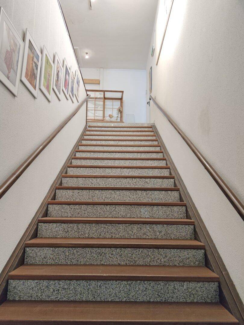 Treppenhaus mit Holzstufen, Steinakzenten und einem Holzgeländer.