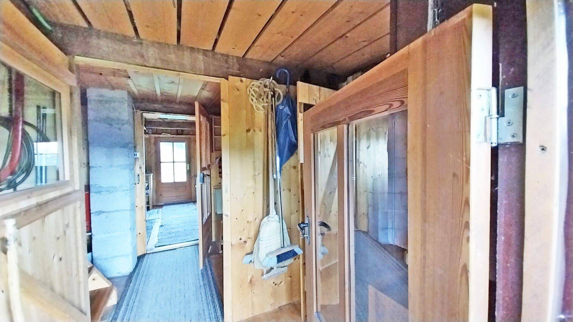 Schmaler Flur mit Holzwänden und -decken, der zu weiteren Räumen in der Hütte führt.