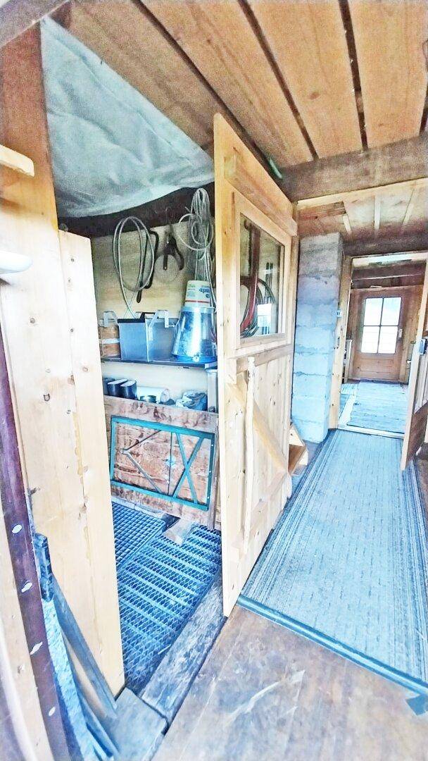 Kleiner Abstellraum mit Holzwänden und Regalen, ideal zur Aufbewahrung von Utensilien.