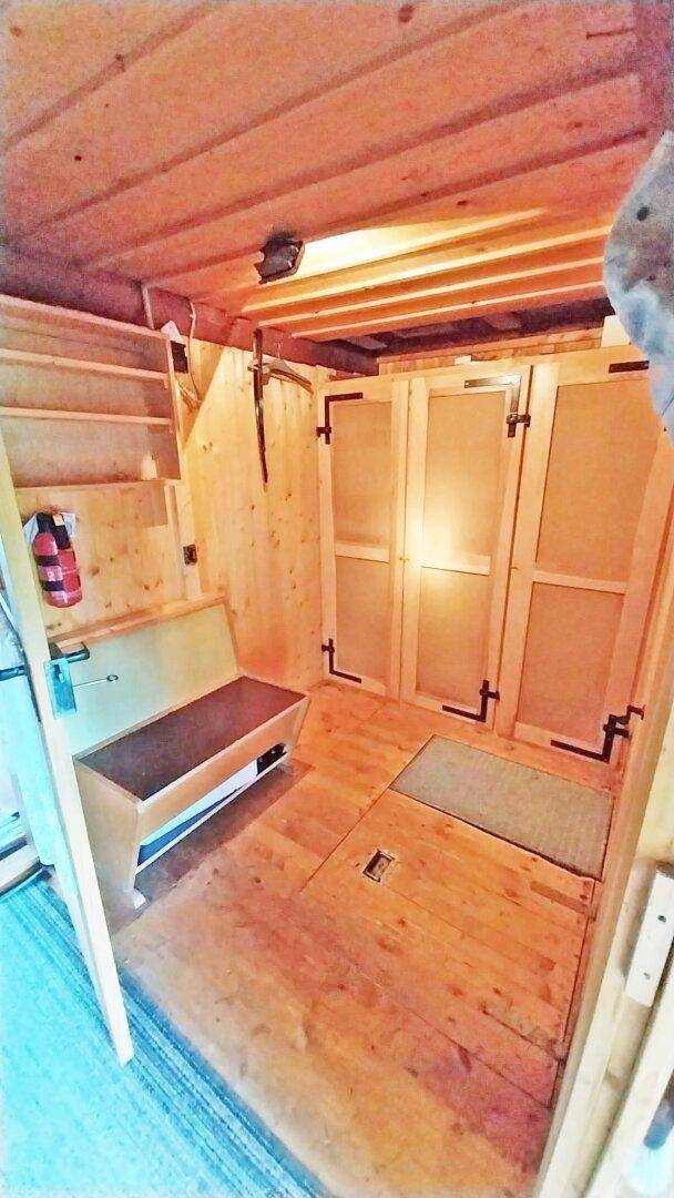 Kleiner Raum mit Holzboden und -wänden, ausgestattet mit einer einfachen Holzbank.