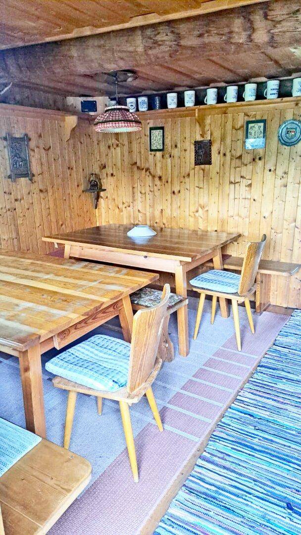 Gemütlicher Essbereich in einer Holzhütte mit Holztischen, Stühlen und traditioneller Dekoration.