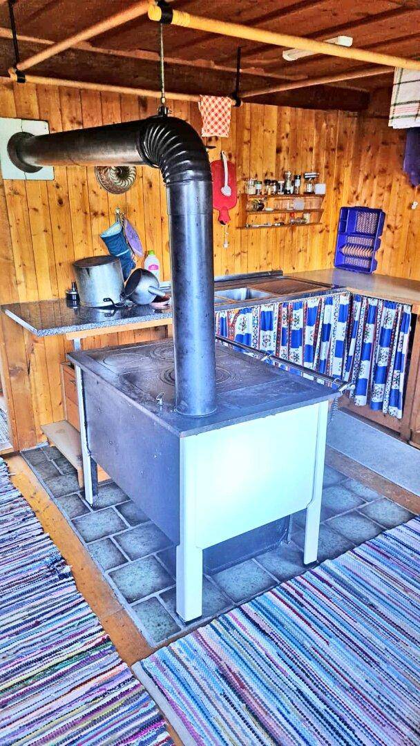 Rustikale Küche mit Holzofen, Arbeitsplatte und farbenfrohem Teppichboden.