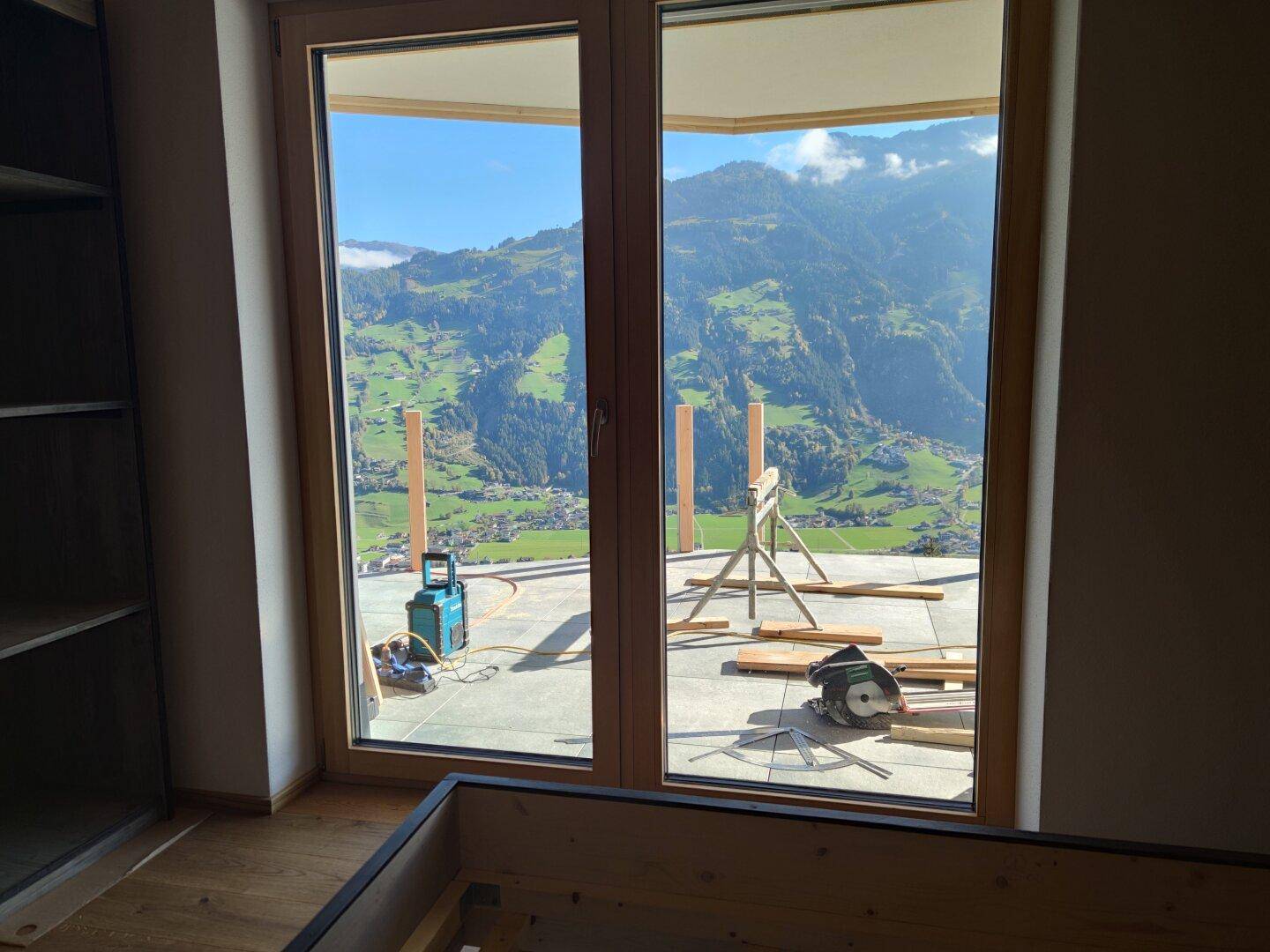 Helles Zimmer mit großem Fenster und Zugang zur Terrasse, bietet einen weiten Blick auf die Berglandschaft.