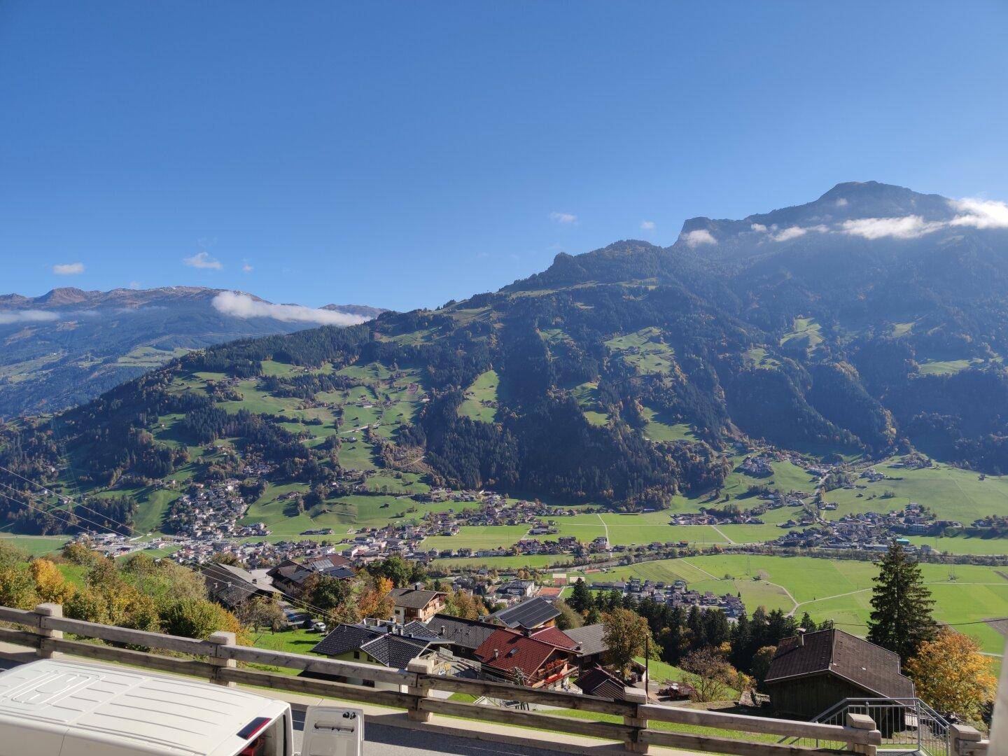 Atemberaubender Panoramablick über das grüne Tal und die majestätischen Berge unter blauem Himmel.