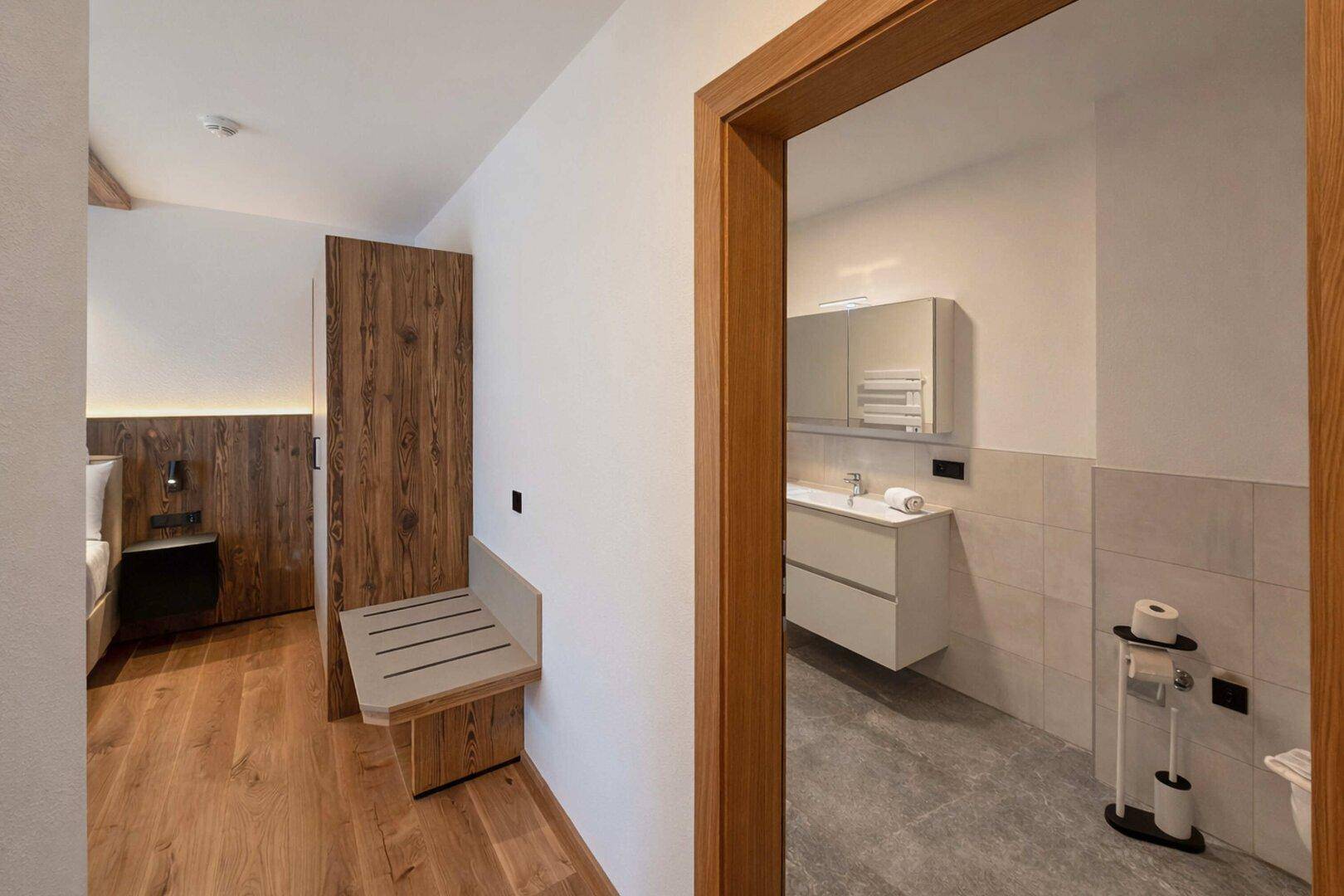 Heller Flur mit Holzboden, Holzakzenten und Blick ins Badezimmer.