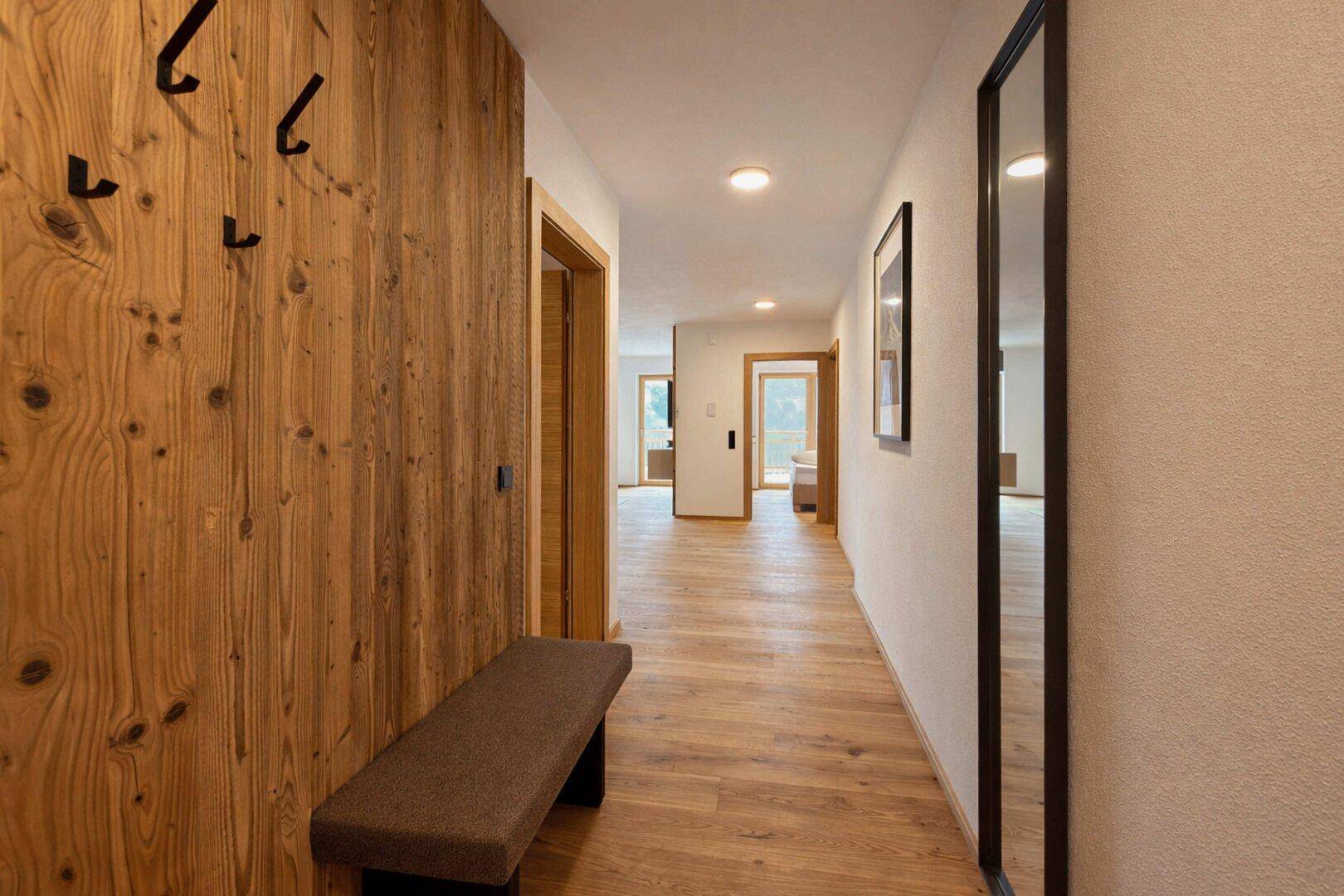 Langer Flur mit Holzboden, Holzwand und Garderobe.