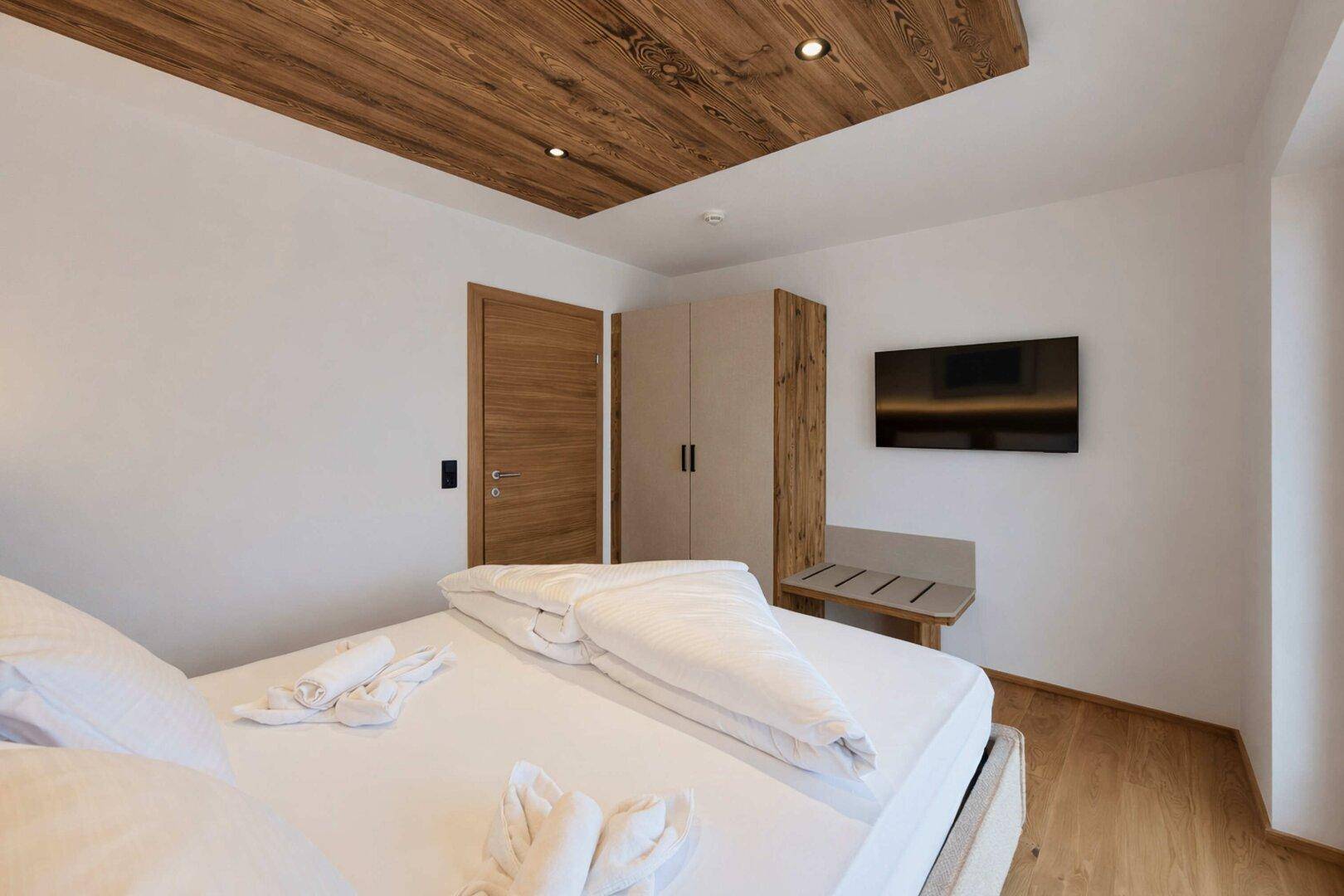 Helles Schlafzimmer mit Holzboden, Holzakzenten und modernem Einbauschrank.