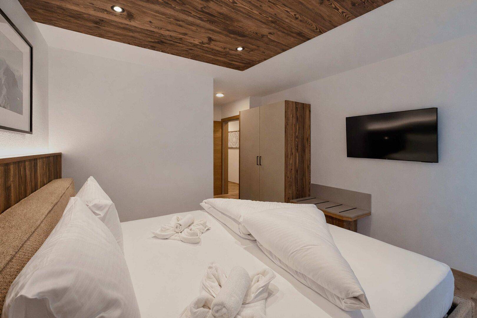Modernes Schlafzimmer mit Holzboden, Einbauschrank und einer stilvollen Holzdecke.