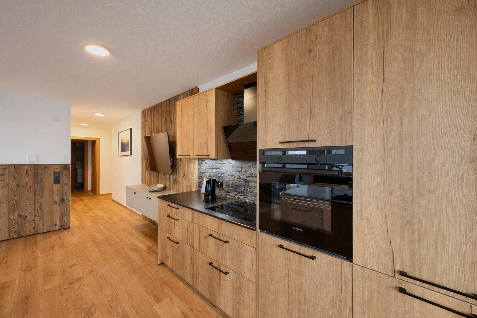 Hochwertige Einbauküche mit modernen Holzfronten und integrierten schwarzen Elektrogeräten.