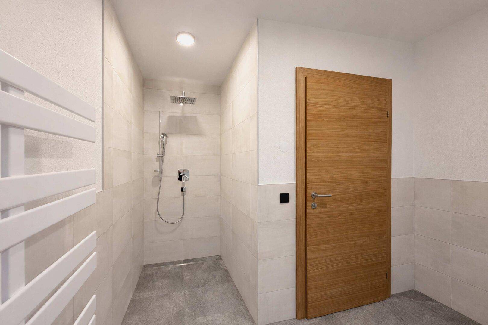 Geräumige, ebenerdige Dusche mit Regenduschkopf und modernen Fliesen im Badezimmer.