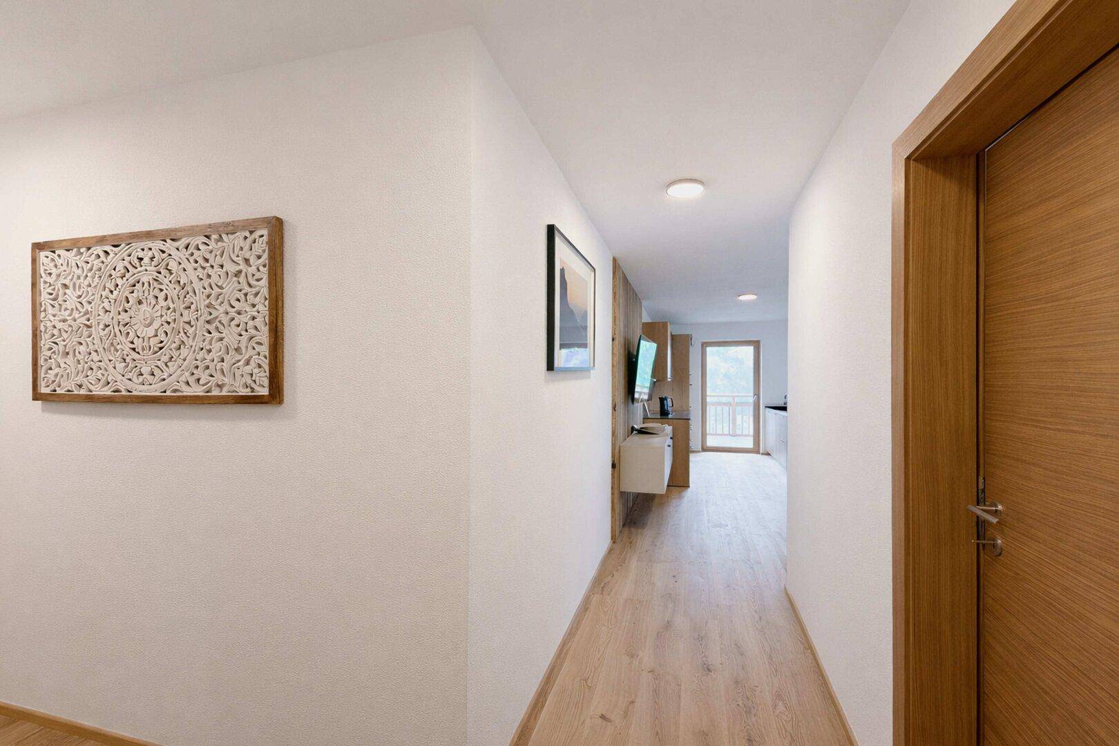Langer, heller Flur mit Holzboden, der zu den verschiedenen Räumen der Wohnung führt.