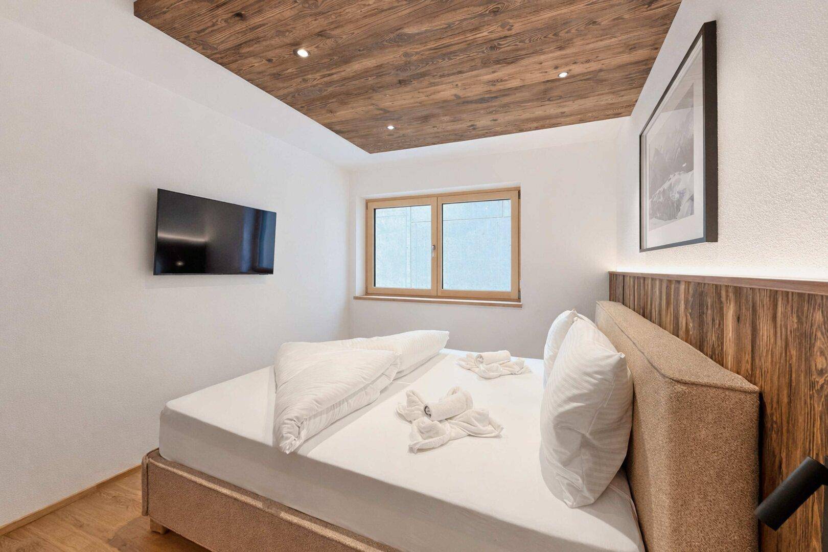 Gemütliches Schlafzimmer mit Holzbett, Holzboden und einer dekorativen Holzdecke.