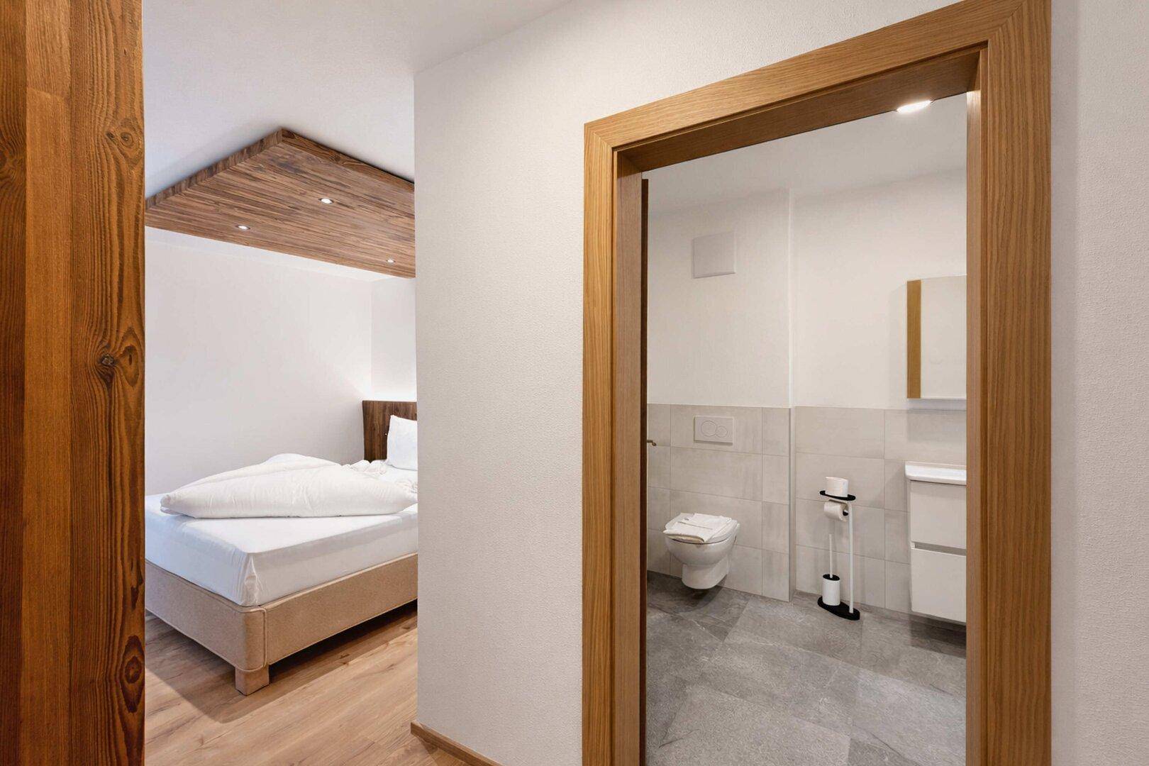 Heller Flur mit Holzboden, der zu einem Schlafzimmer und einem modernen Badezimmer führt.