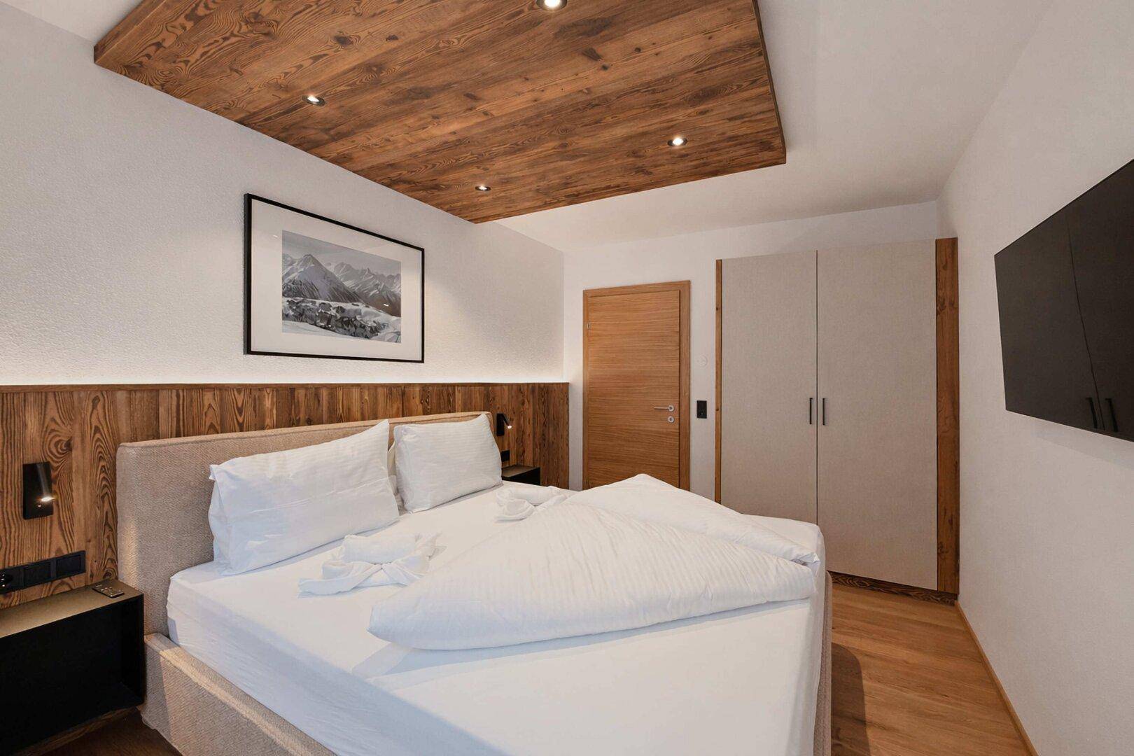 Komfortables Schlafzimmer mit Holzboden, Einbauschrank und einer markanten Holzdecke.