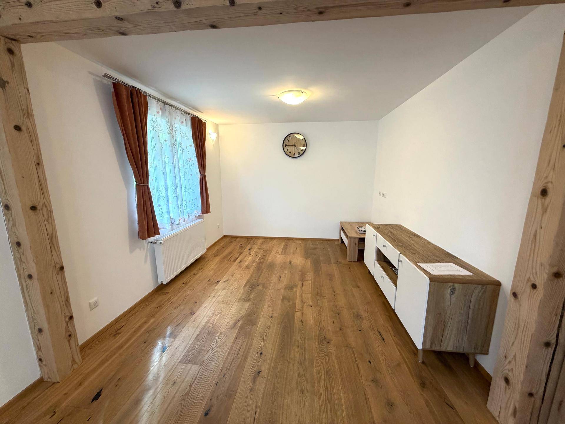 Helles Wohnzimmer mit Holzbalken, Parkettboden und einem modernen Sideboard.
