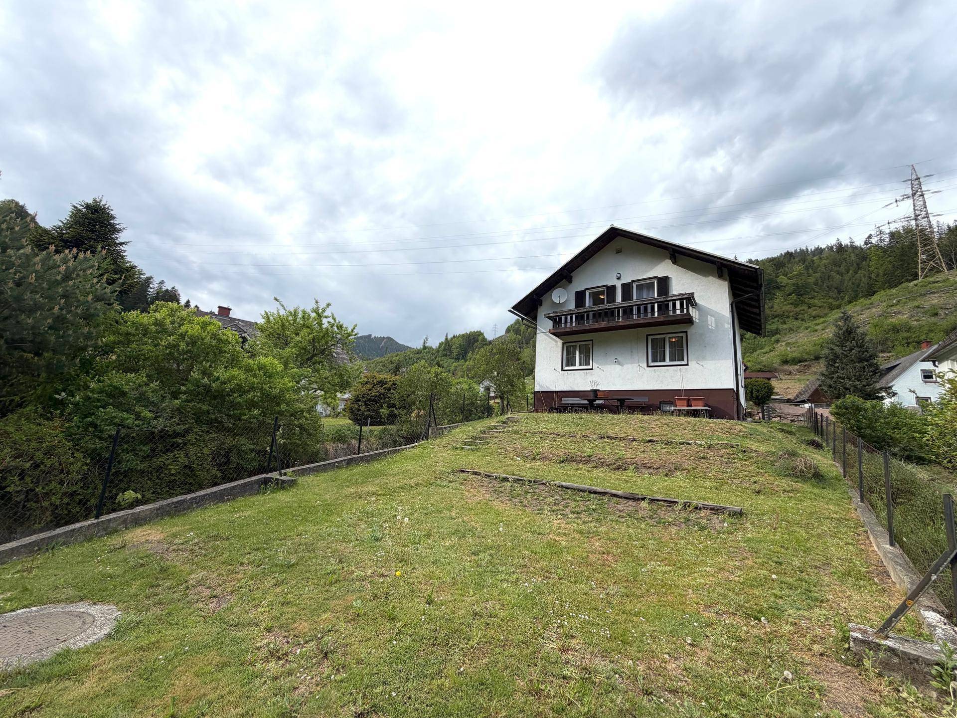 Freistehendes Haus mit Balkon und großem Garten auf einem Hügel mit Blick auf die Umgebung.