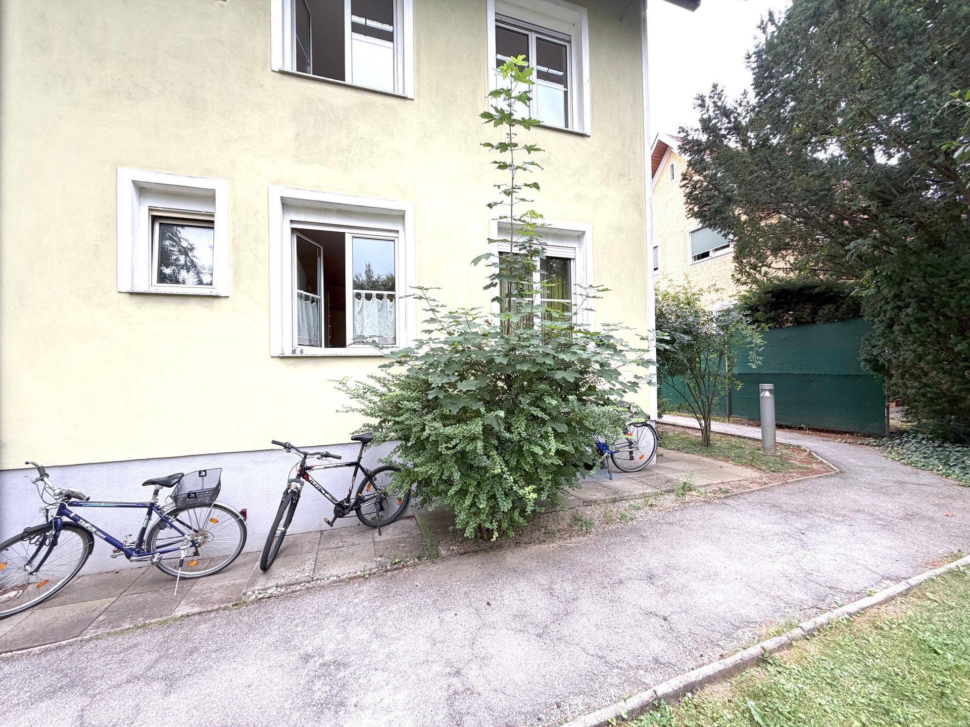 Fassade eines Wohnhauses mit Fenstern und Fahrrädern im Vordergrund.