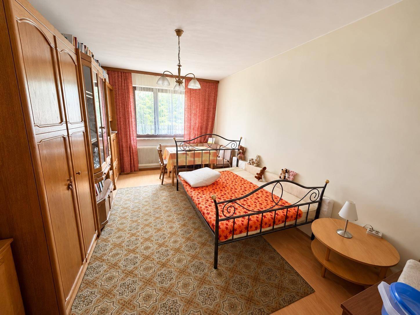 Schlafzimmer mit Einzelbett, Teppichboden und traditionellen Holzschränken.