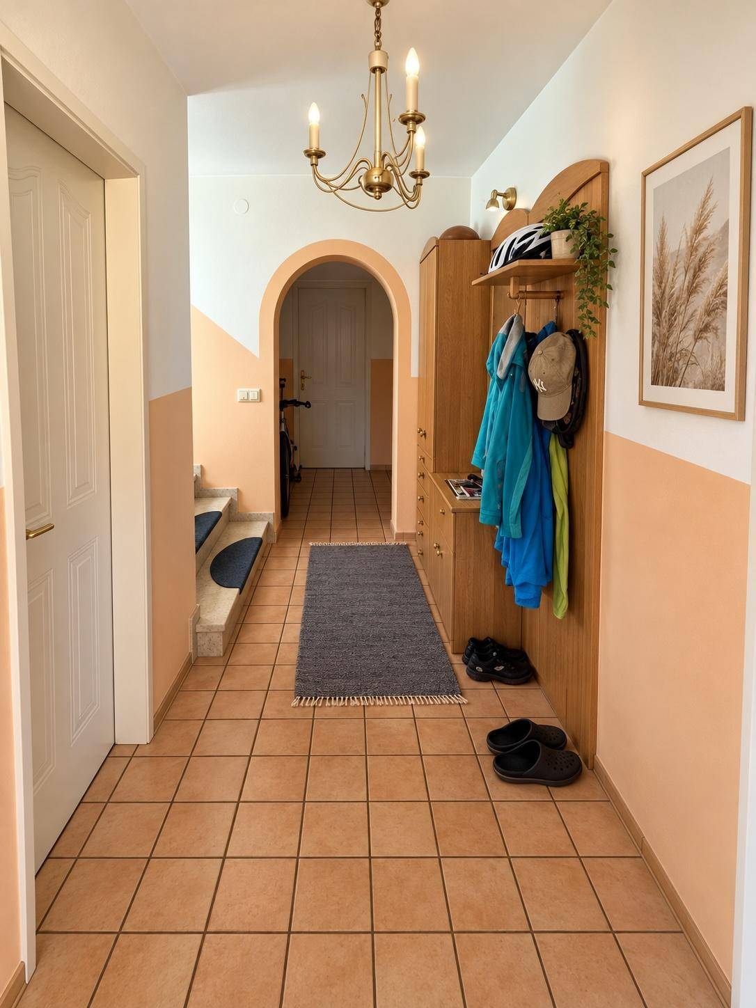 Heller Eingangsbereich mit Fliesenboden, Garderobe und einer Treppe zum Obergeschoss.