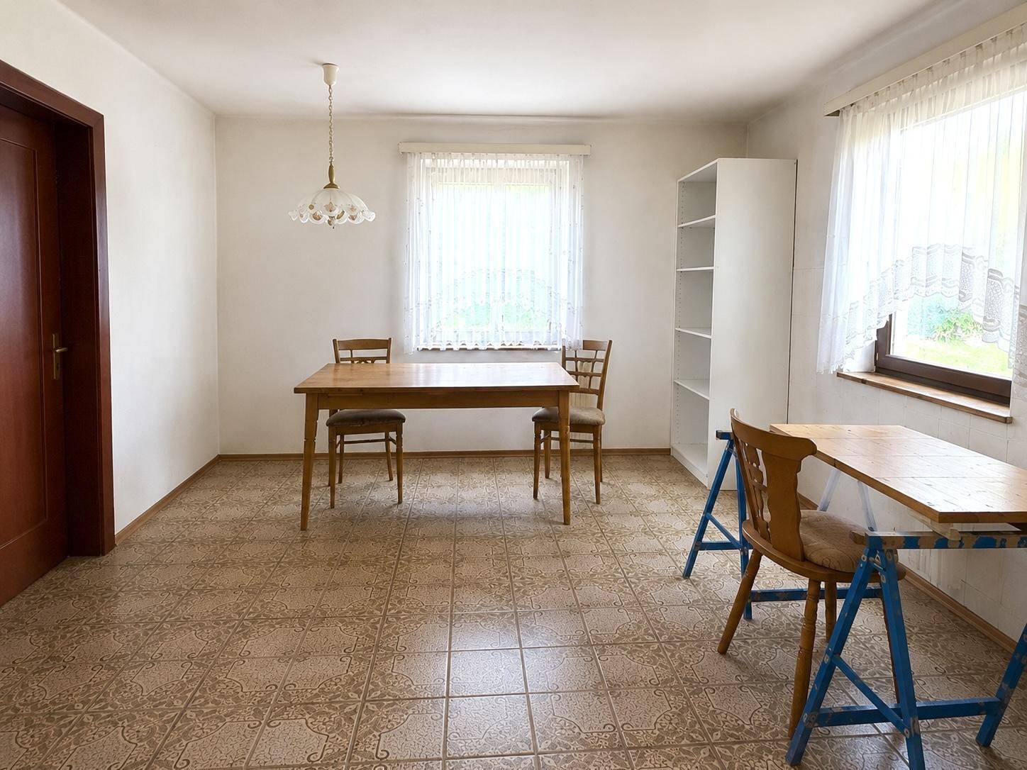 Geräumiger Essbereich mit Holztisch und Stühlen, hellen Wänden und gefliestem Boden.
