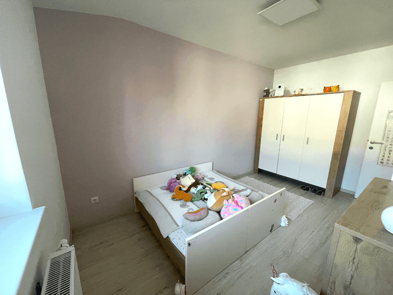 Geräumiges Kinderzimmer mit Bett, Kleiderschrank und sanfter Wandfarbe.
