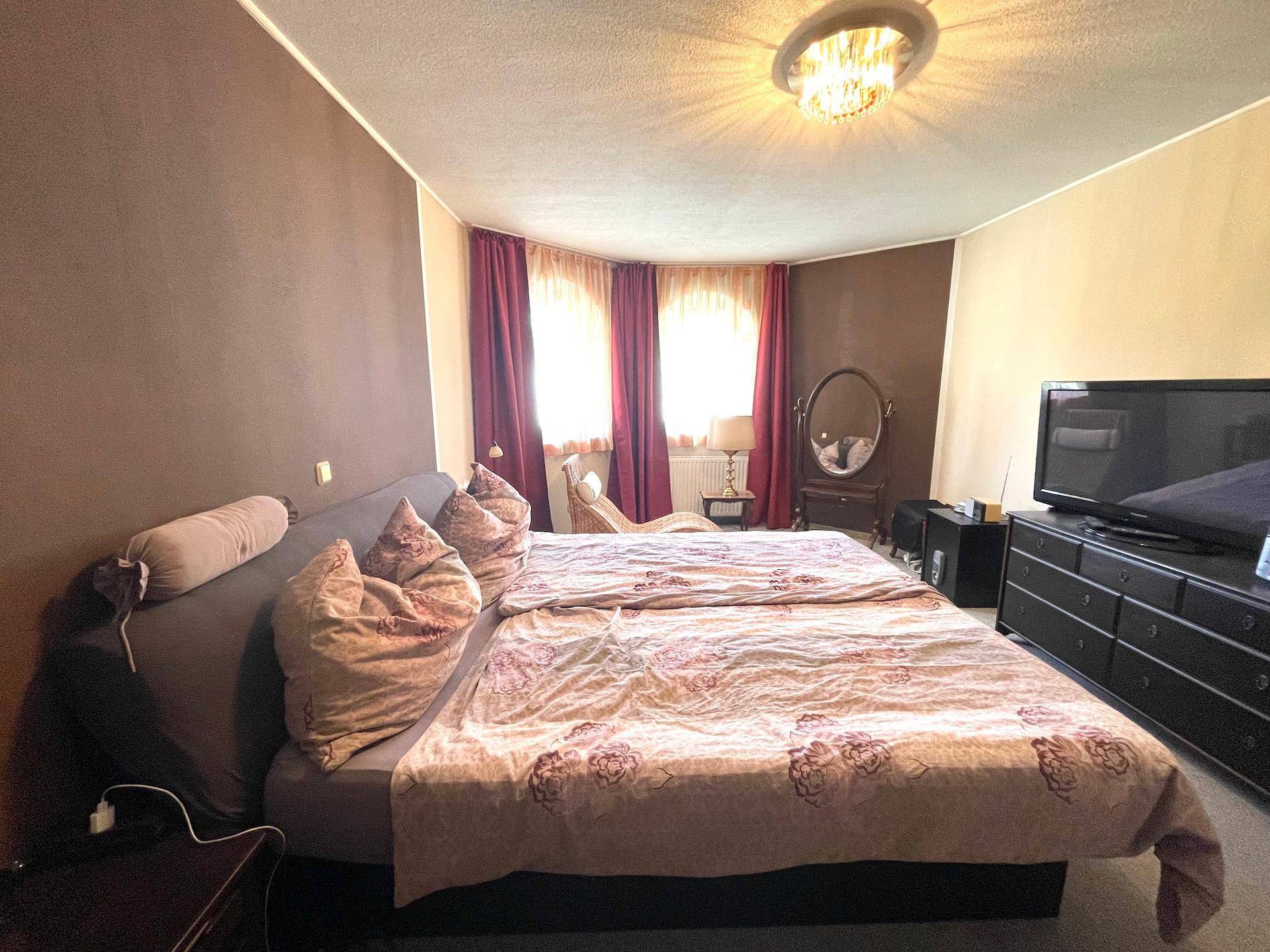 Ein Schlafzimmer mit großem Doppelbett, Schminktisch und warmer Farbgestaltung.