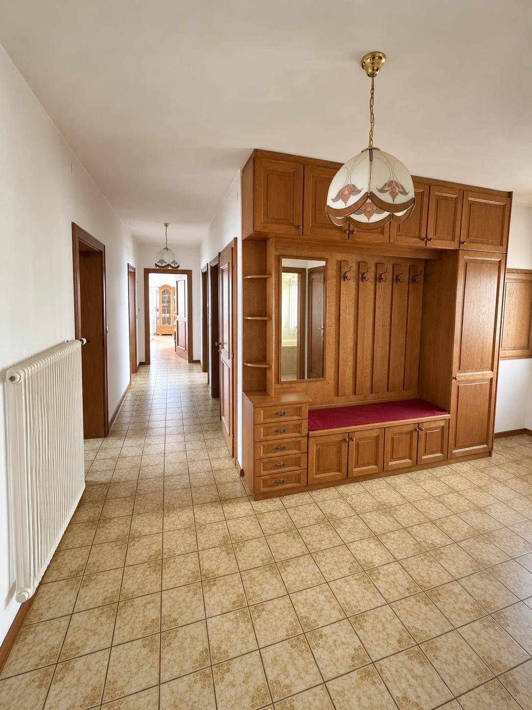 Geräumiger Flur mit Fliesenboden, Einbauschränken und Blick in den hinteren Bereich des Hauses.