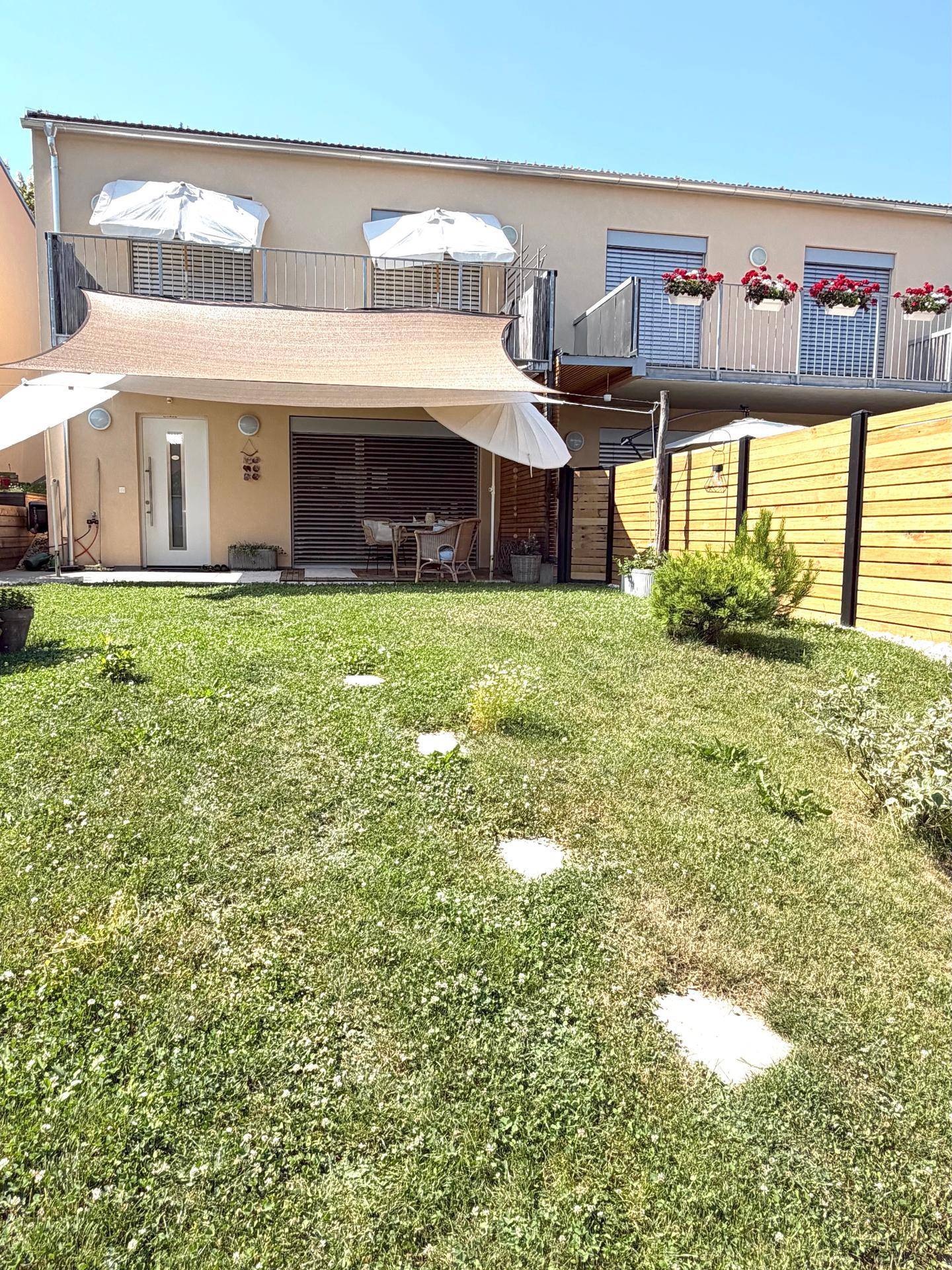 Rückansicht des Hauses mit Terrasse im Erdgeschoss und Balkonen im Obergeschoss.