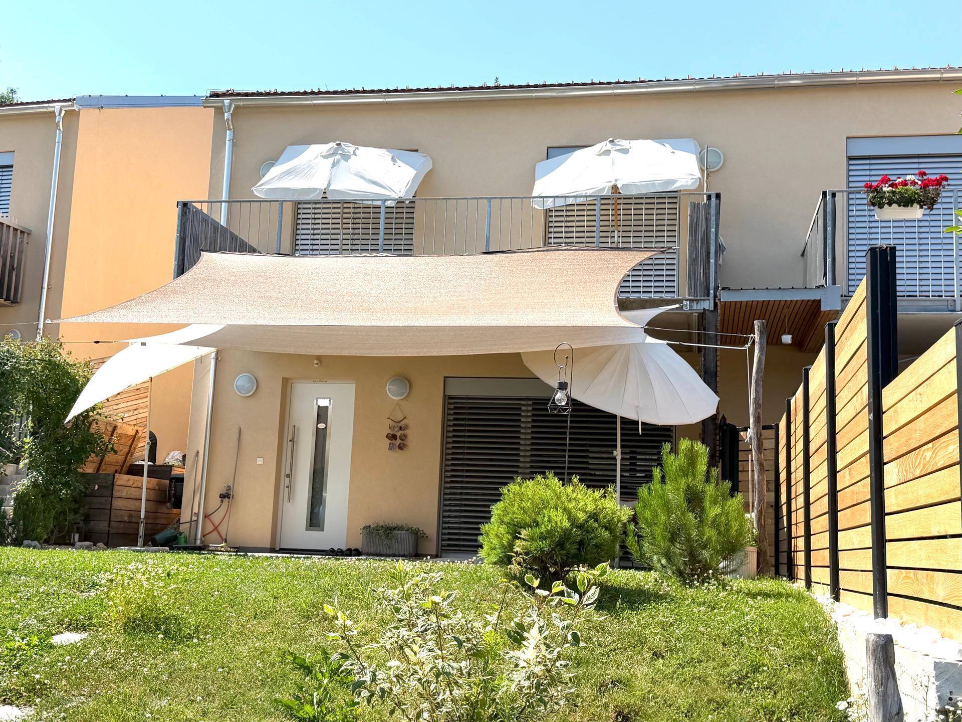 Ansicht der Hausrückseite mit mehreren Balkonen und einer großzügigen Terrasse.